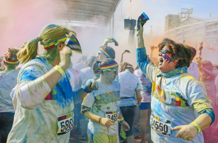 Baltimore, MD -- April 19, 2014 -- Runners celebrate the finish line by dousing each other with powder at the Color Run on Saturday morning. The popular course is a 5K where runners get bombarded with handfuls of colored powder throughout the race. (Kaitlin Newman for Baltimore Sun)